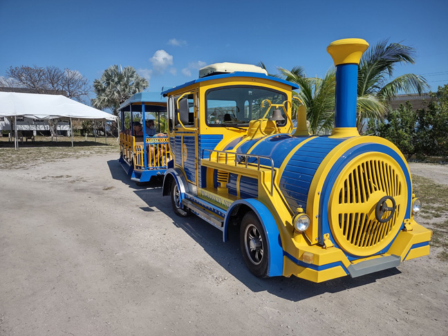 The colorful blue and yellow rubber tire trolly in front of a tent on Pigeon Key