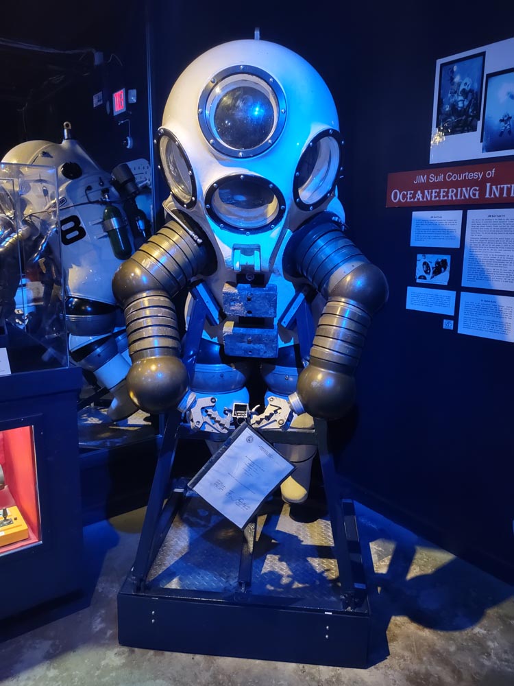 A modern robotic dive suit with articulated arms and claws for hands at the History of Diving Museum.