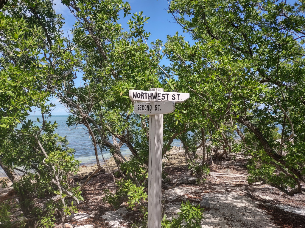 A rustic wooden street signpost at the intersection, with the streets "Northwest St" and "Second St" on Indian Key