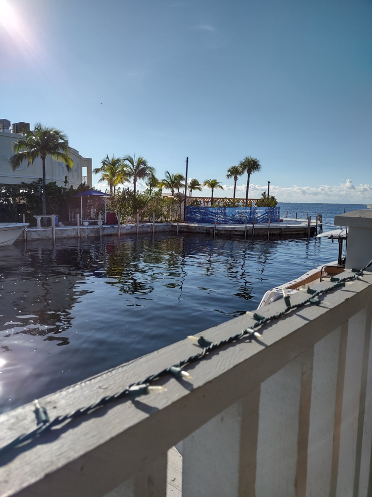 A patio looks across a canal with palm trees, blue water, and blue sky in the gateway to the Florida Keys: Key Largo

