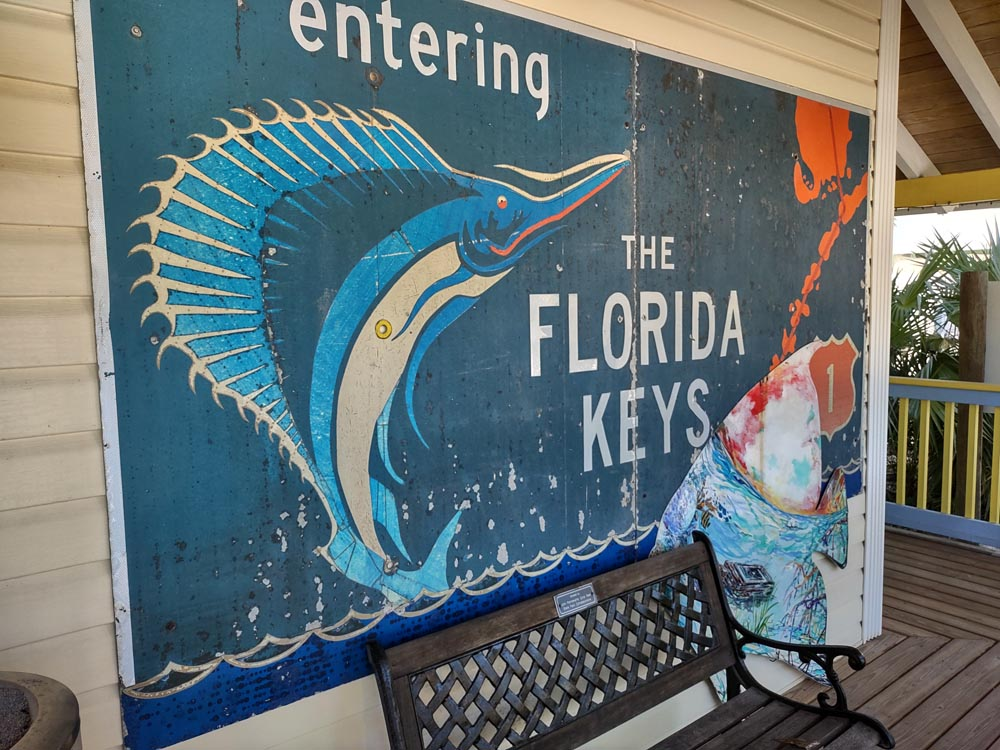 A sailfish jumps out of the water next to the line of Florida Keys in a retro poster on the front of a building in the Gateway to the Florida Keys: Key Largo