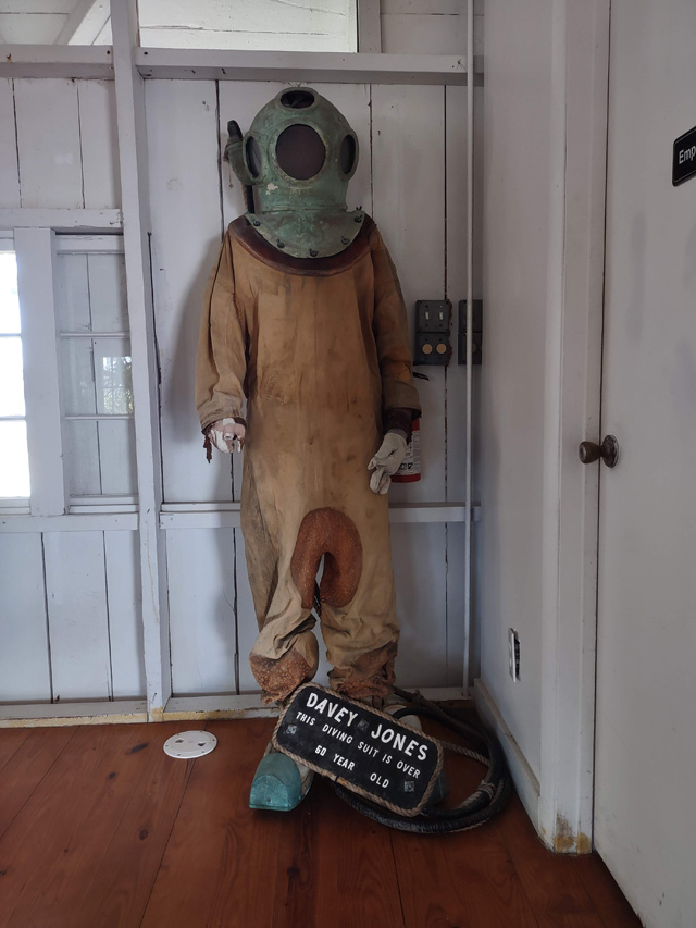 An over 50-year-old tan diving suit with a steel helmet stands in the corner of the museum on Pigeon Key